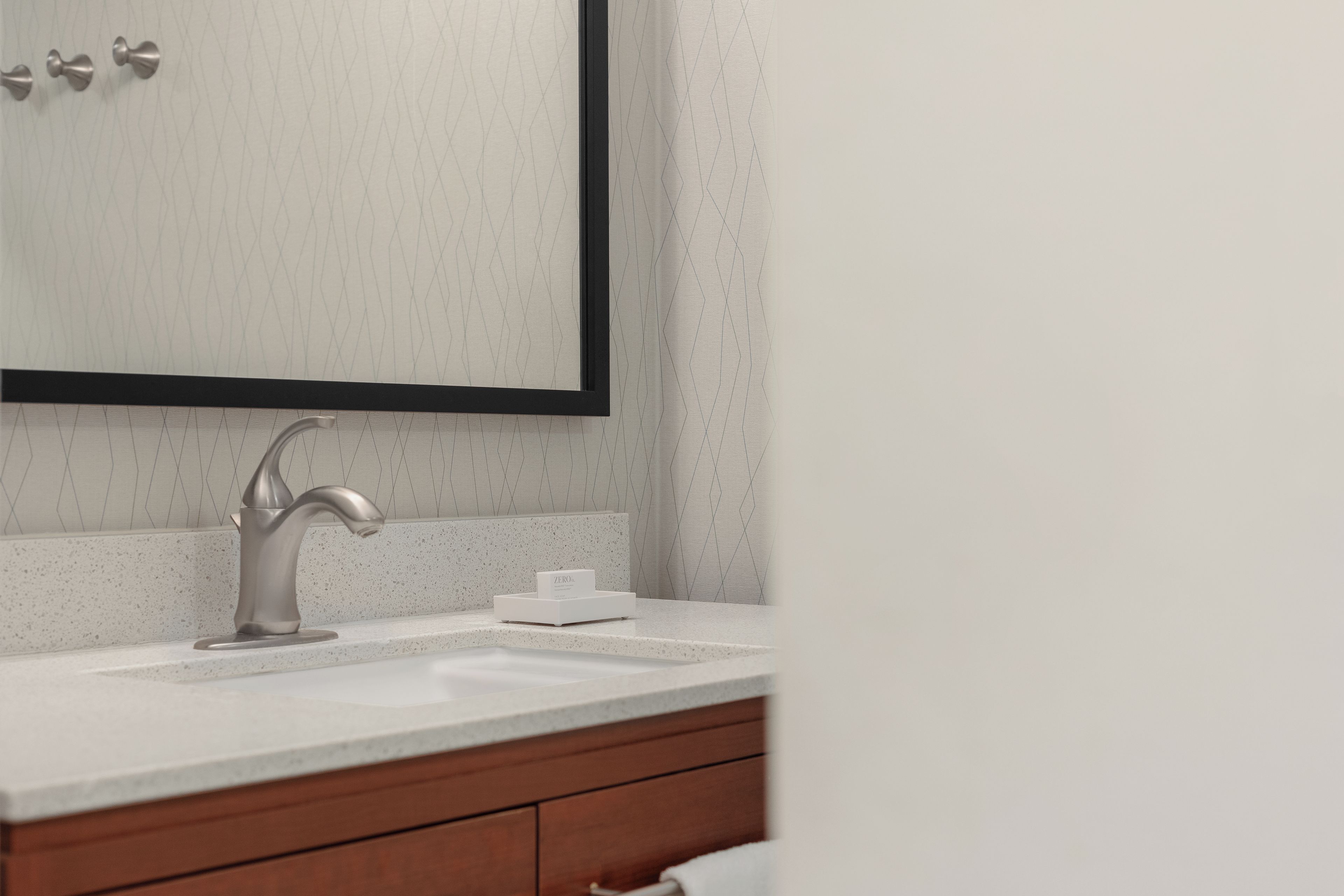 A bathroom with a modern sink, a mirror, and a towel rack.