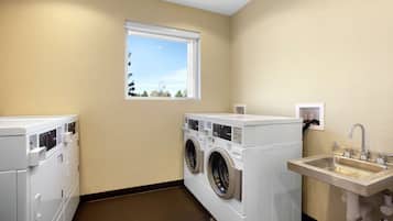Un cuarto de lavado con dos lavadoras, un lavabo y una ventana.