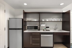 A modern kitchen with a built-in refrigerator, microwave, coffee maker, and a sink with a faucet.