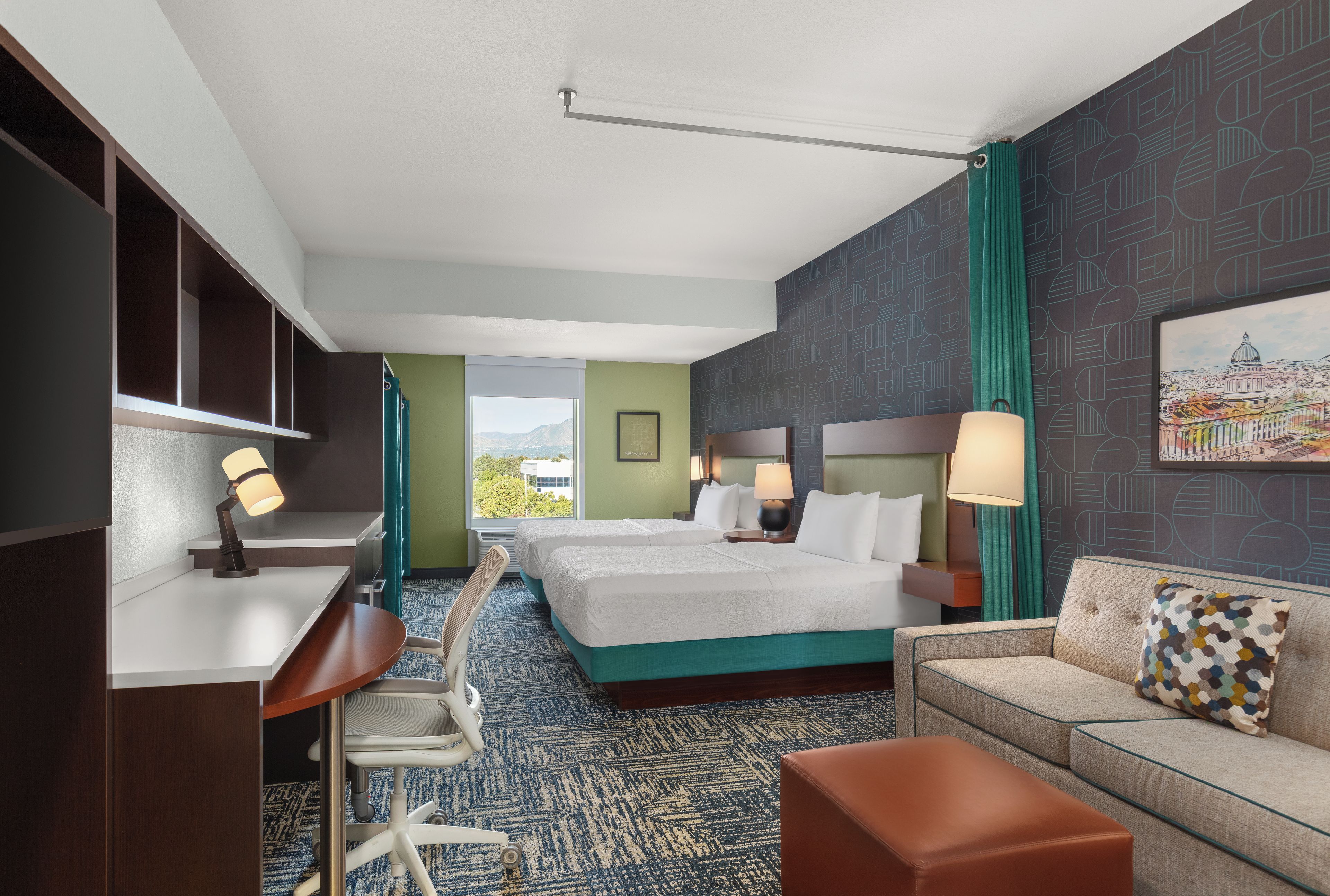 A hotel room with two beds, a desk, a chair, a sofa, and a large window offering a view.