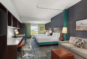 A hotel room with two beds, a desk, a chair, a sofa, and a large window offering a view.