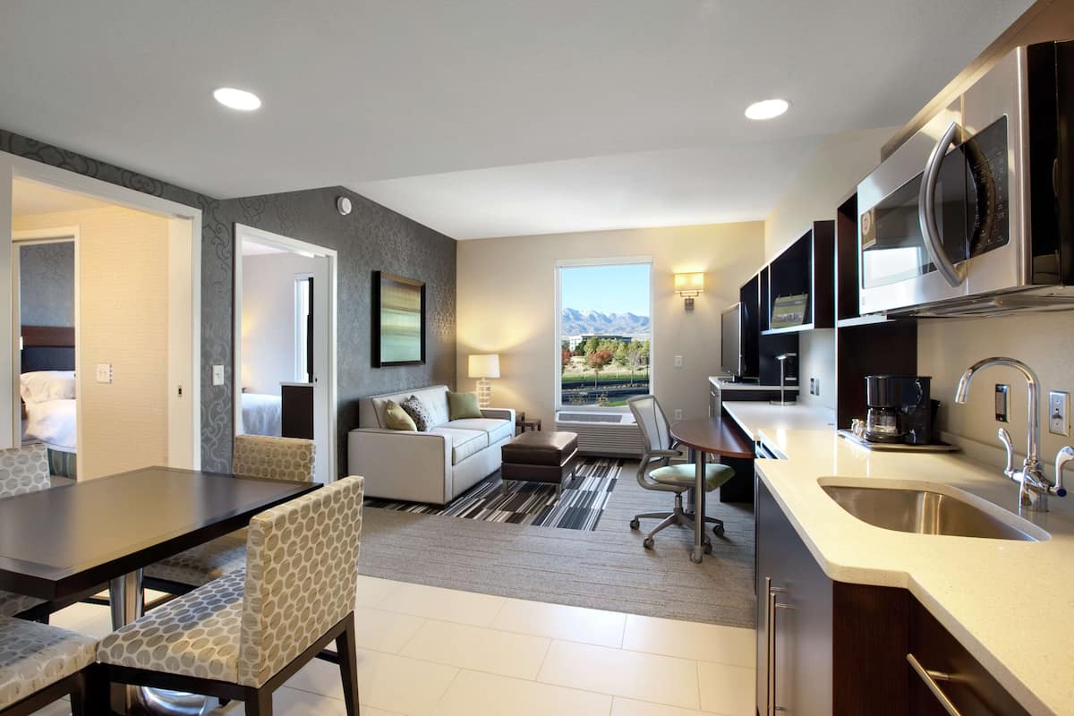 A modern kitchen with a large island, built-in appliances, and a view of mountains.