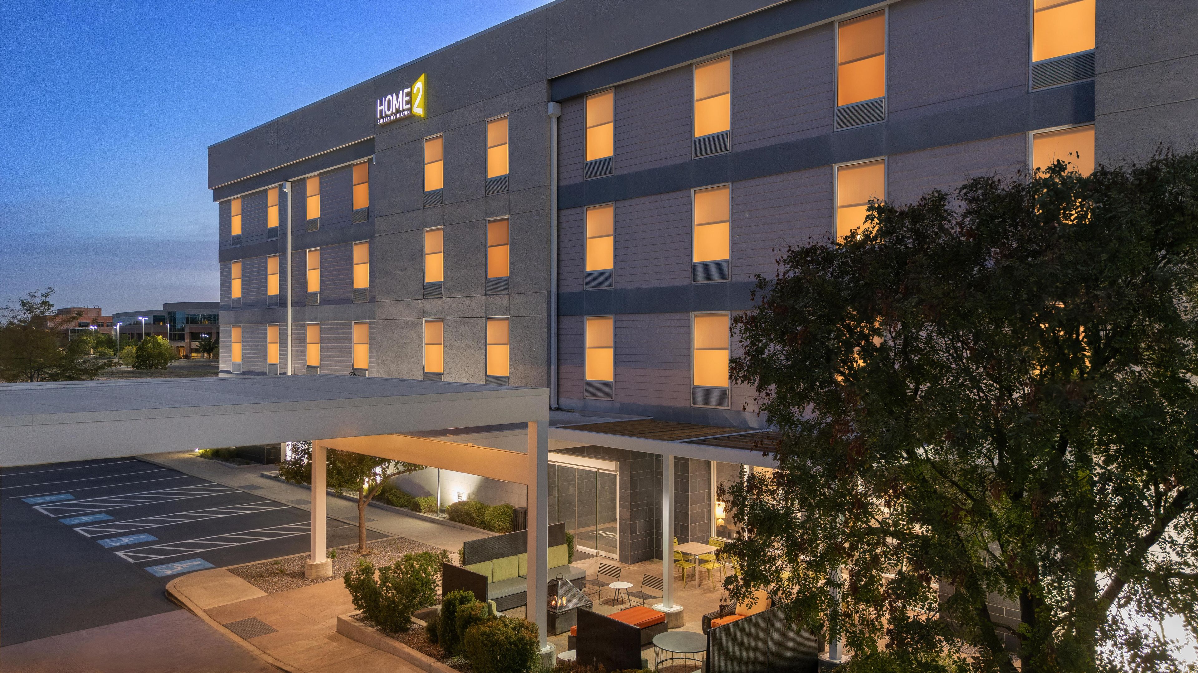 A hotel with a modern exterior, multiple windows, and an outdoor seating area with tables and chairs.