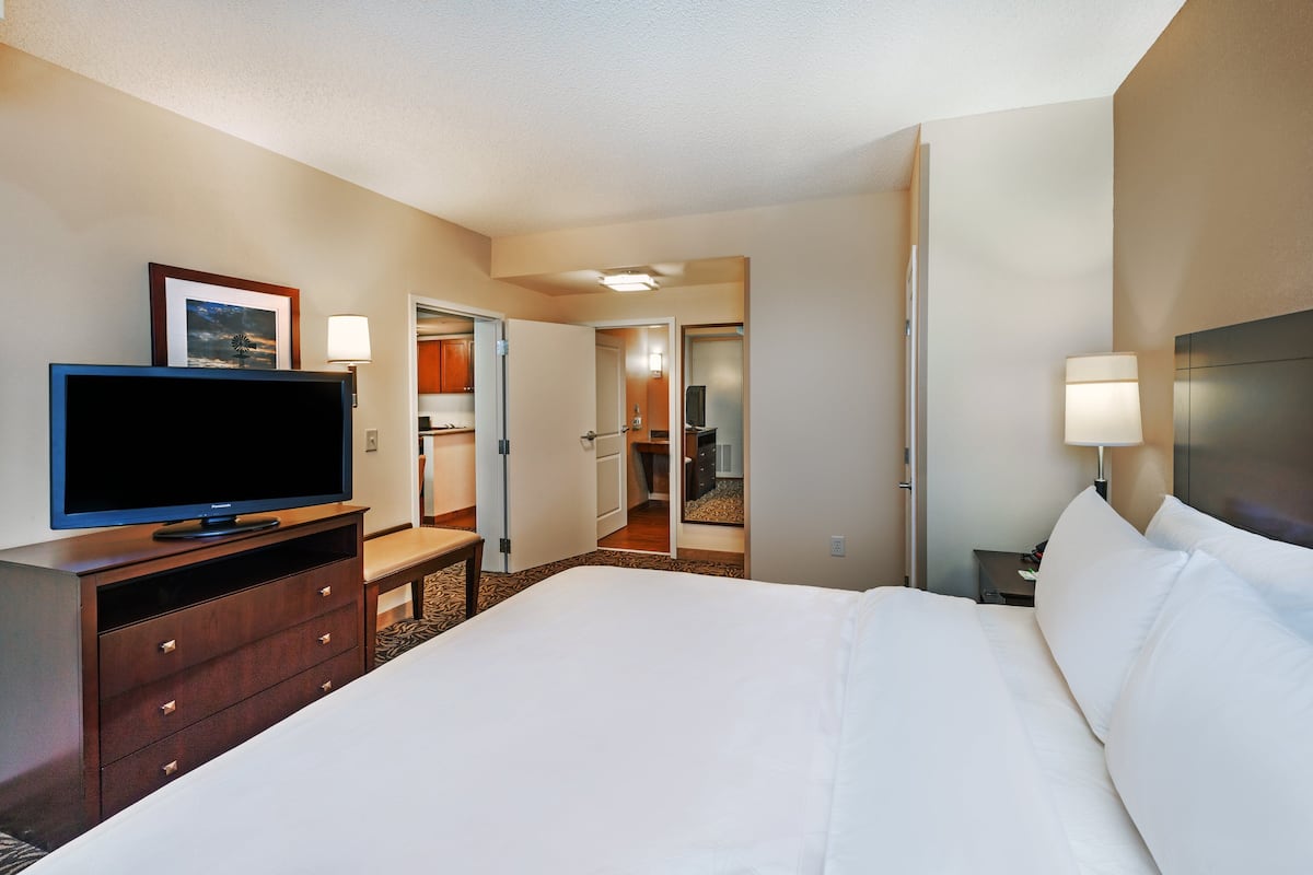 A hotel room with a large bed, a TV on a wooden dresser, and a mirror on the wall.