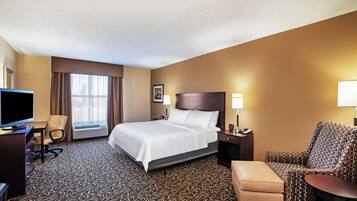 A hotel room with a bed, desk, chair, and television.