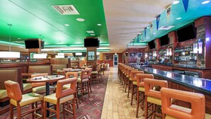 A bar area with multiple seating options, including booths and bar stools, and a counter with a variety of beverages.