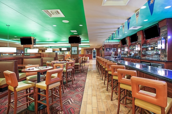 Zona de bar con diversas opciones de asientos, incluyendo cabinas y taburetes, y una barra con una variedad de bebidas.