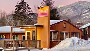 A lodge named 'Cadence' with a wooden exterior, a covered porch, and a mountain backdrop. - Cadence Lodge at Whiteface (Wilmington)