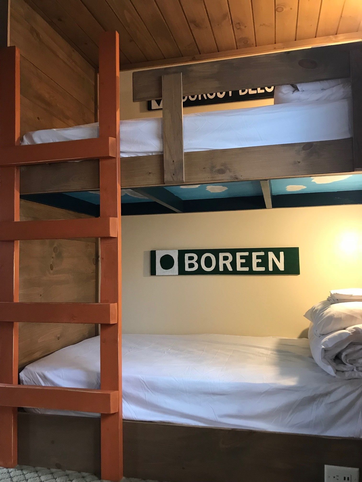 A bunk bed room with a ladder, a sign that says "Boreen", and a wall-mounted shelf.