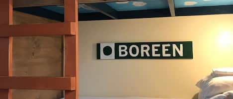 A bunk bed room with a ladder, a sign that says "Boreen", and a wall-mounted shelf.