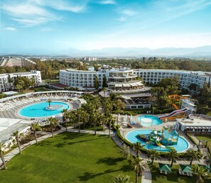 A resort with multiple swimming pools, a water park, and a view of distant mountains.