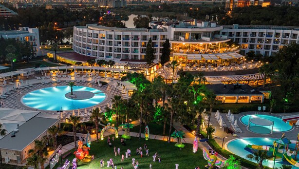 A resort with multiple swimming pools, a large central pool, and a well-maintained lawn area with palm trees. - Kaya Side - All Inclusive (Manavgat)