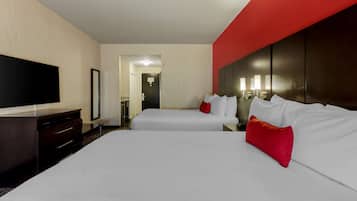 Une chambre d’hôtel avec deux lits, un téléviseur à écran plat, une commode et un mur d’accent rouge.