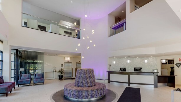 A spacious lobby with a central seating area, a reception desk, and a staircase leading to an upper level.