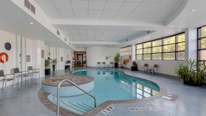 A swimming pool with a 1.00m depth marker, surrounded by lounge chairs and potted plants.