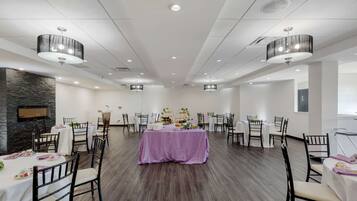 Un salón de banquetes con mesas redondas, sillas y un arreglo floral central.