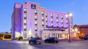 A hotel with a modern facade, multiple floors, and a parking lot with several cars.