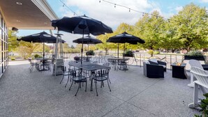 An outdoor patio with tables and chairs, umbrellas, and string lights.