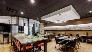 A modern dining area with a long table, multiple chairs, and a high ceiling with recessed lighting.