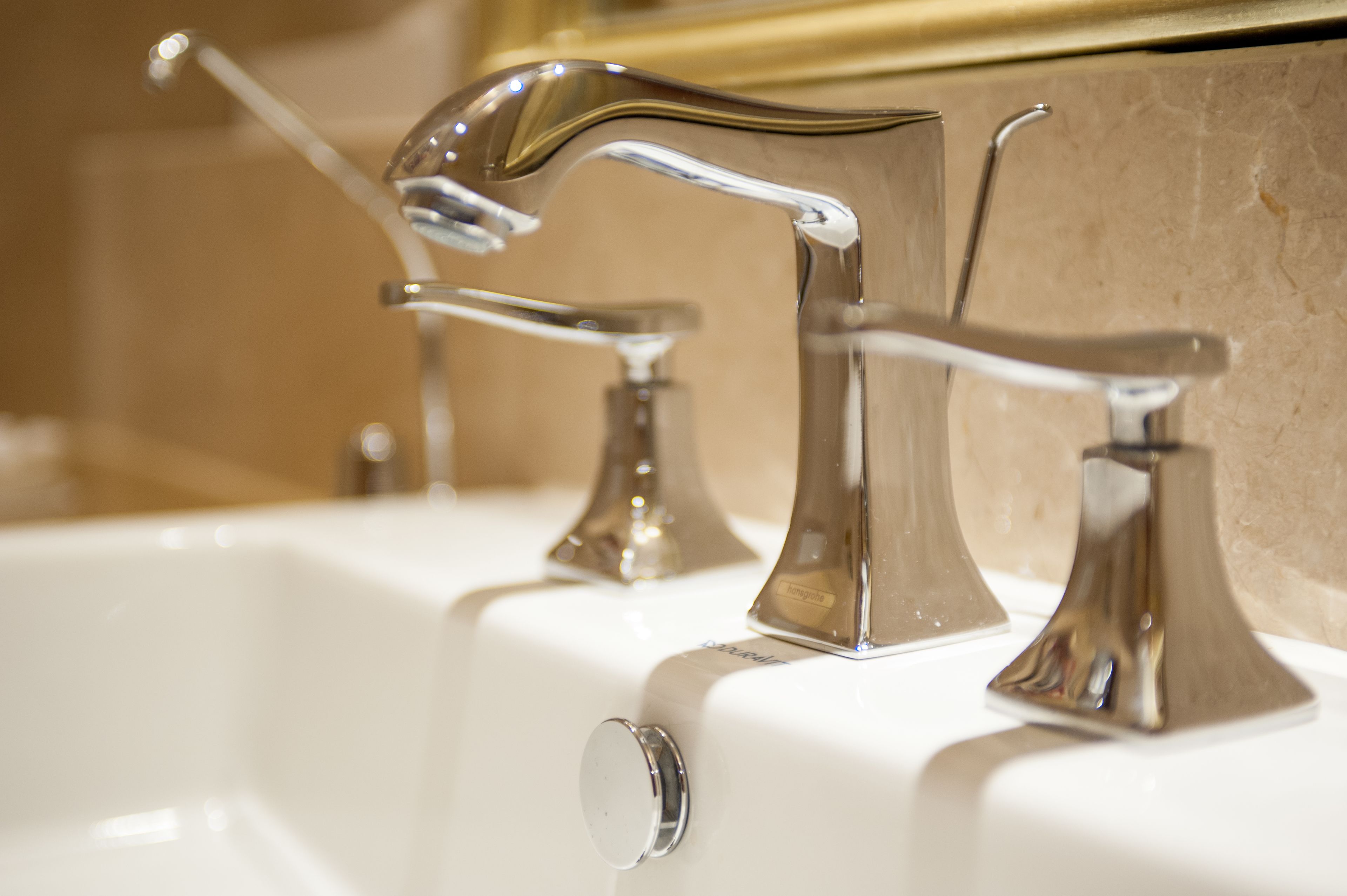 A bathroom with three chrome faucets on a white sink.