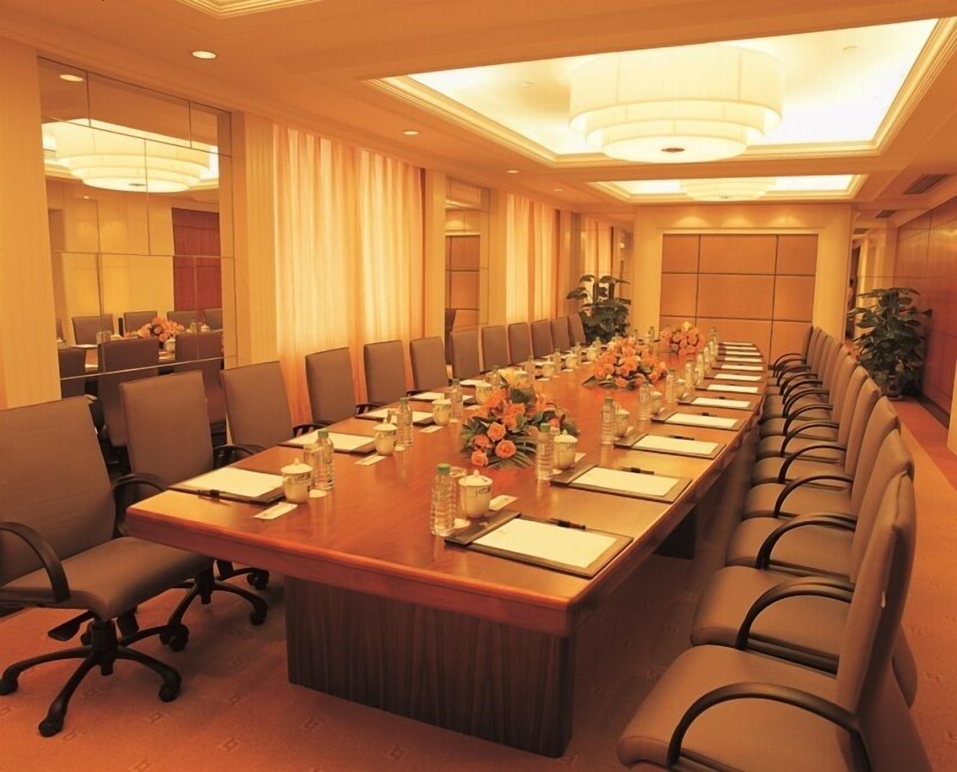 A conference room with a long table, chairs, and floral centerpieces.