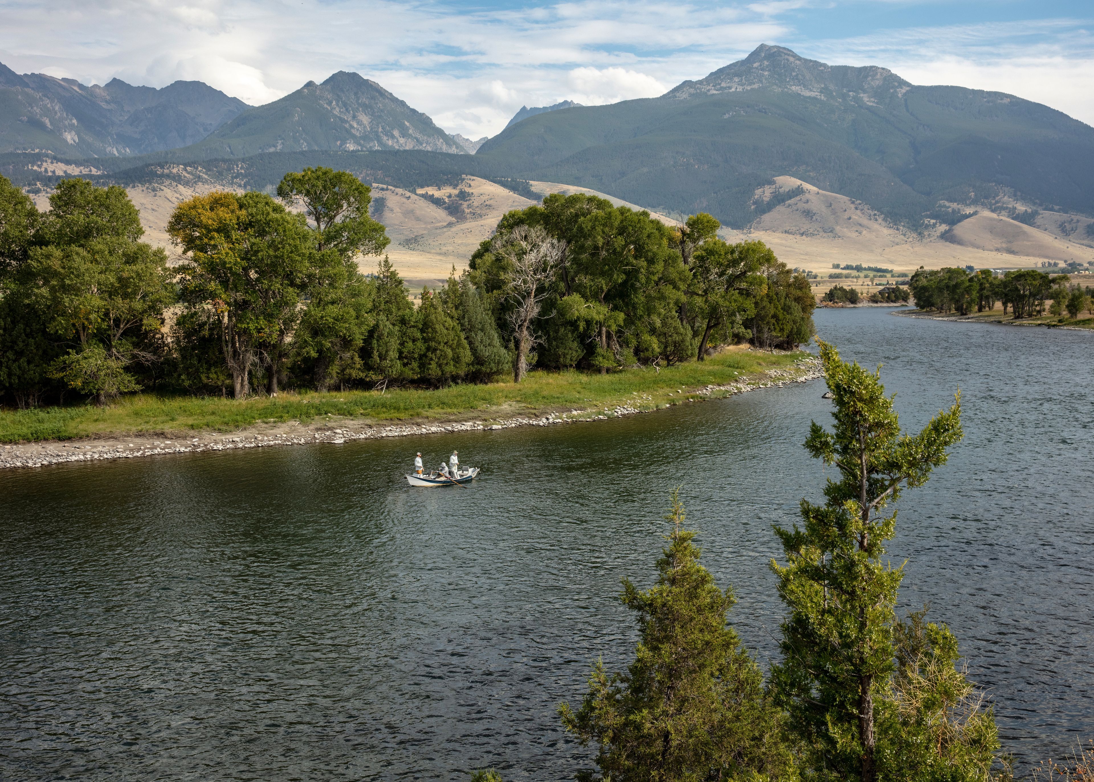 A river with a boat, surrounded by mountains and trees.