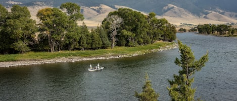 A river with a boat, surrounded by mountains and trees.