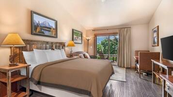 A hotel room with a bed, two bedside tables, a desk, a chair, a TV, and a balcony with curtains.