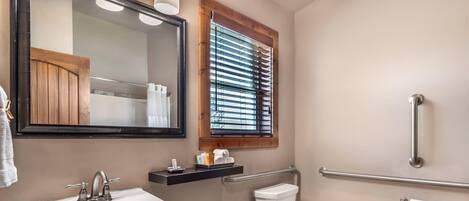 Une salle de bain avec un lavabo, des toilettes et une fenêtre équipée de stores.