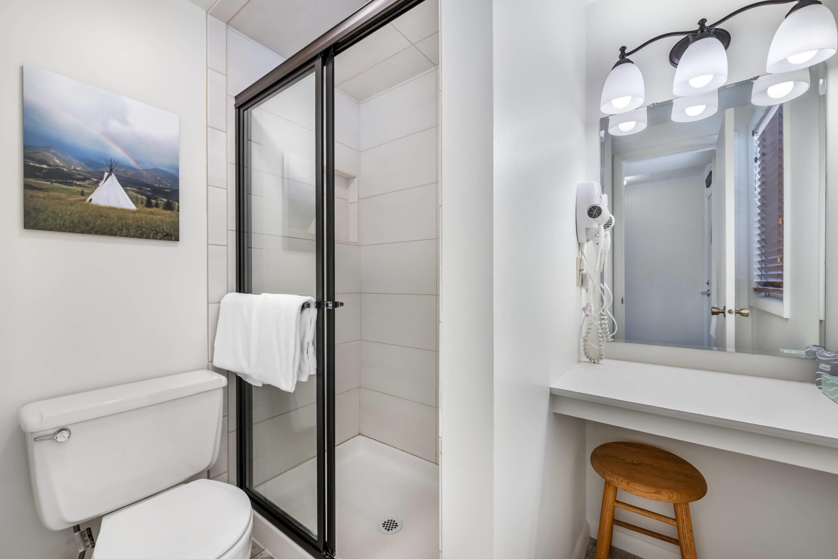A modern bathroom with a glass shower enclosure, a white toilet, a sink with a mirror, and a towel rack.