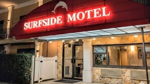 The exterior of the Surfside Motel with a prominent red awning displaying the motel's name and a dolphin logo. - Surfside Motel (Howard Beach)
