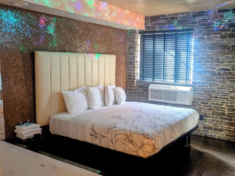Un dormitorio moderno con una cama grande, cabecera y ventana con persianas.