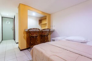 Una habitación de hotel con una cama, dos sillas, una mesita y una puerta.
