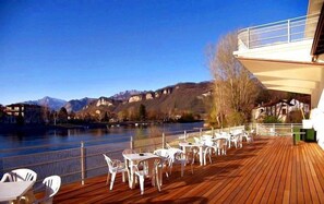 Eine Holzterrasse mit Sitzgelegenheiten im Freien mit Blick auf einen Fluss und Berge.