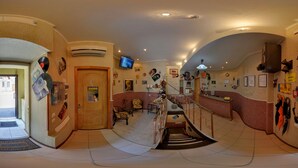 A spacious hallway with a staircase leading to a second floor, decorated with various wall art and a mounted television. - YELLOW UNLIMITED HOTEL 4 (Kharkiv)