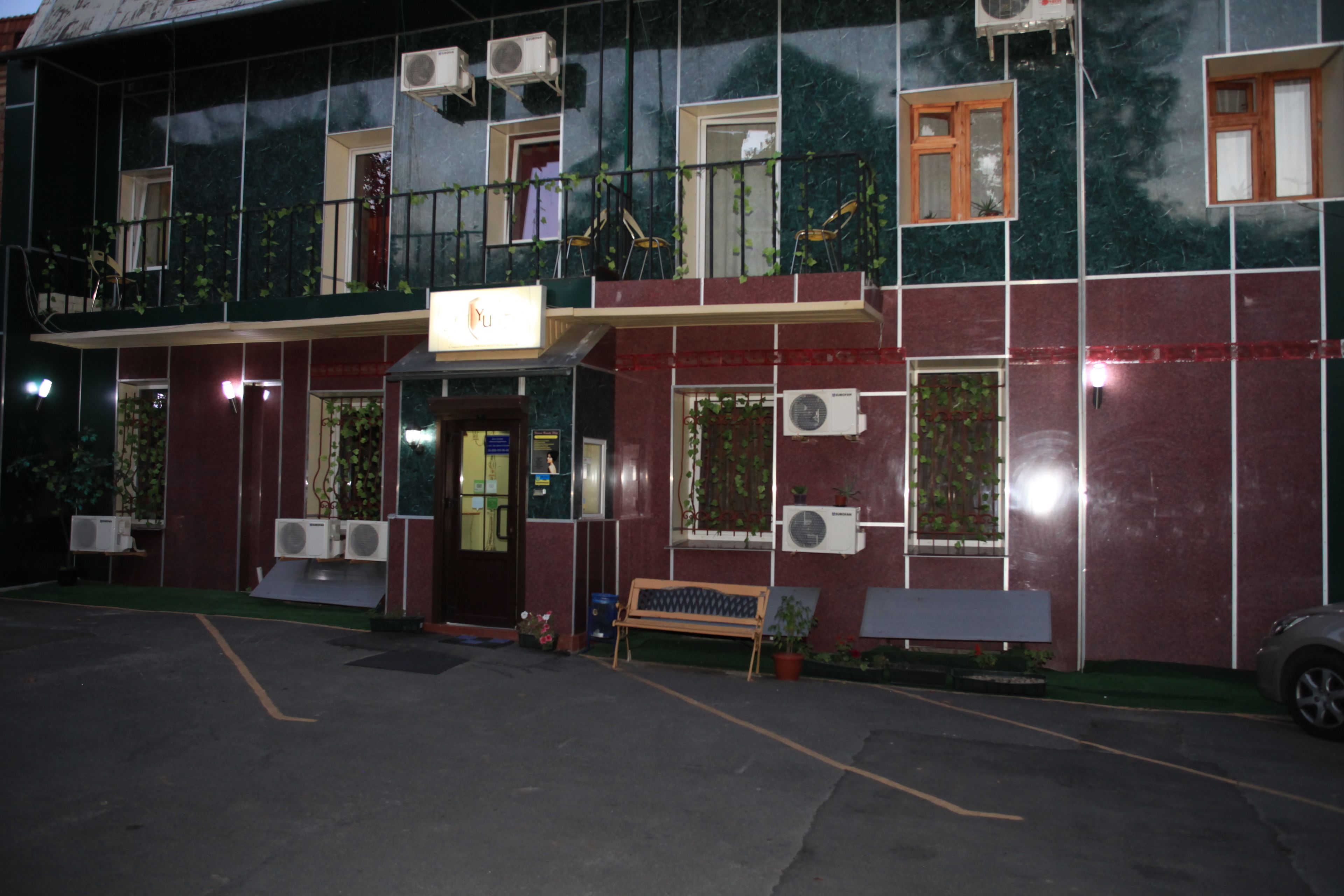 A building with multiple balconies, air conditioning units, and a bench outside.