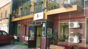 A hotel entrance with a wooden bench, potted plants, and an air conditioning unit. - YELLOW UNLIMITED HOTEL 4 (Kharkiv)