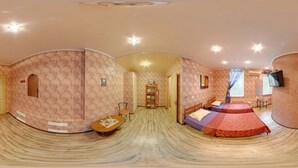 A panoramic view of a hotel room with a curved ceiling, patterned wallpaper, two beds with red and purple bedding, a wooden table with teapots, a bookshelf, and a television mounted on the wall. - YELLOW UNLIMITED HOTEL 4 (Kharkiv)