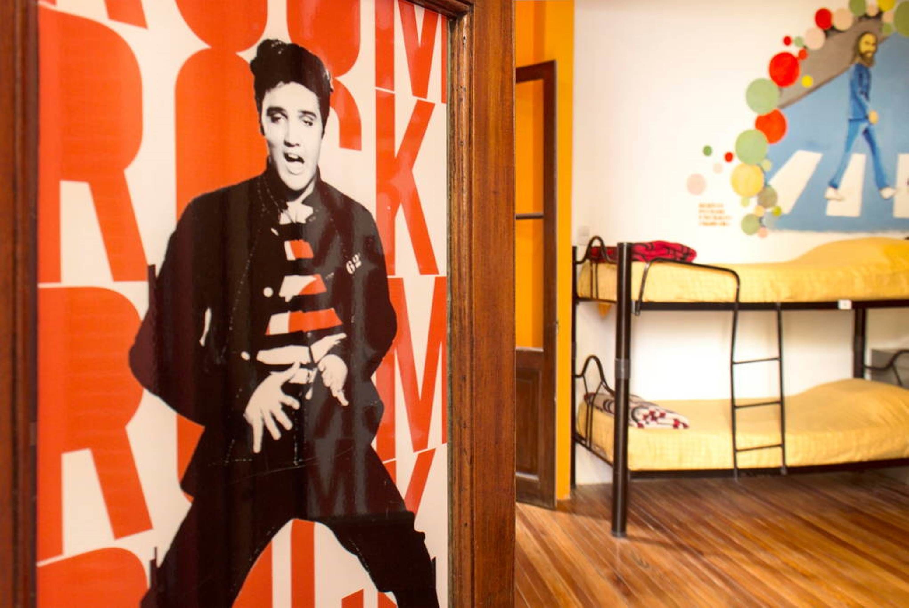 A room with a bunk bed, a poster with a large 'R' on the wall, and a colorful mural.