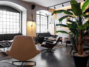 A modern lounge area with leather seating, a large potted plant, and large windows allowing natural light. - Browns Downtown Hotel (Lisbon)