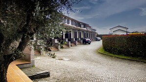 Une rue résidentielle bordée de maisons de ville, avec une allée pavée et une haie sur le côté droit.