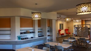 Un restaurant avec un comptoir, plusieurs tables et des chaises.