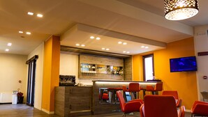 Un espace bar avec des sièges, un téléviseur et une cuisine en arrière-plan.