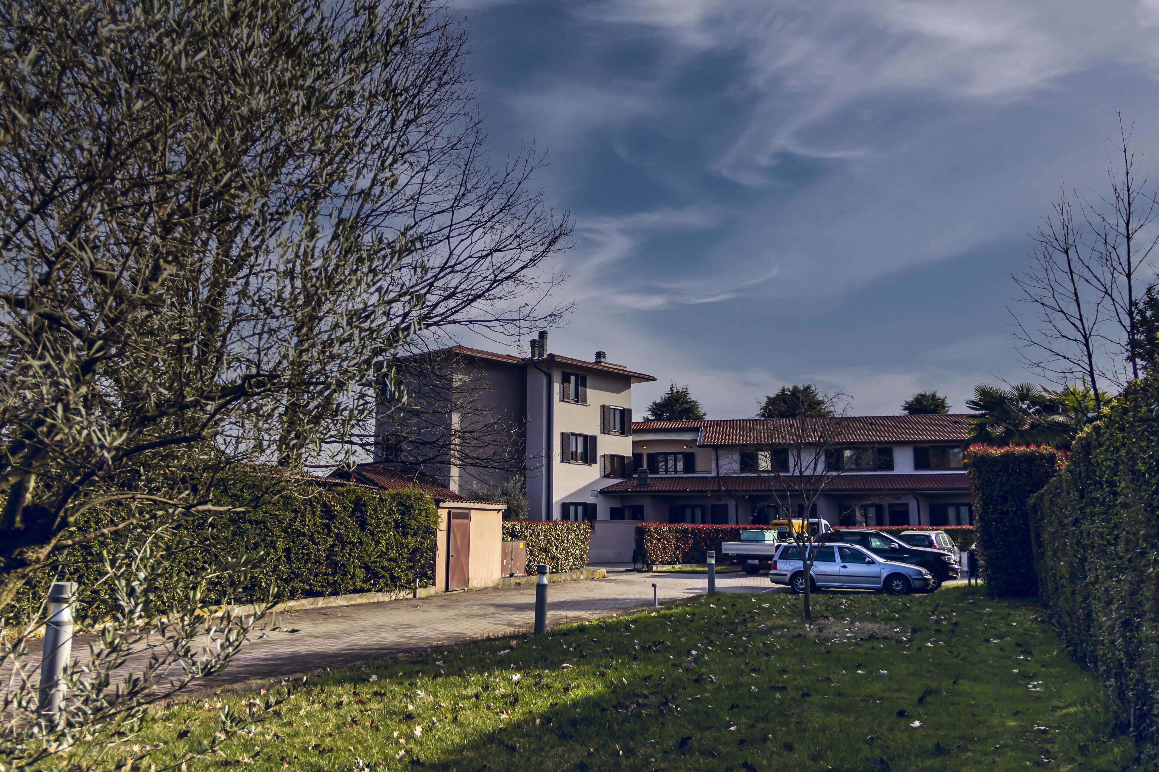 Un quartier résidentiel avec un immeuble à plusieurs étages, des voitures garées et une pelouse bien entretenue.