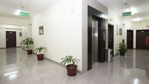 A clean, modern hallway with potted plants, an elevator, and exit signs. - Samara Hotel (Muscat)