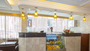 A restaurant area with a marble counter, glass display case with fruits, and hanging pendant lights. - Samara Hotel (Muscat)
