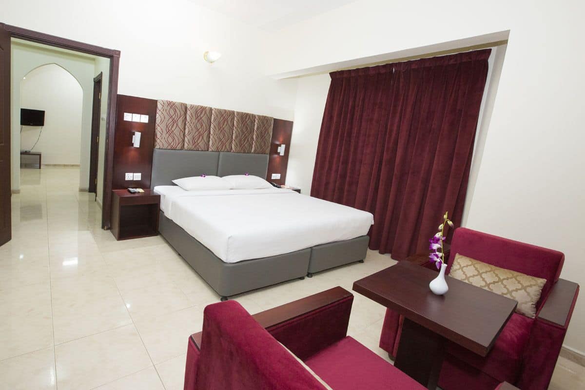 A hotel room with a bed, a desk, a chair, and a small table.