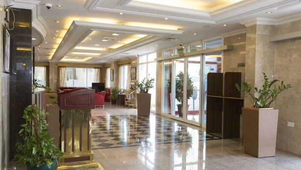 A spacious lobby with a checkered floor, a reception desk, and potted plants. - Samara Hotel (Muscat)