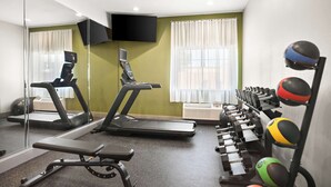 Una palestra con tapis roulant, una panca e un'attrezzatura per esercizi con palle.