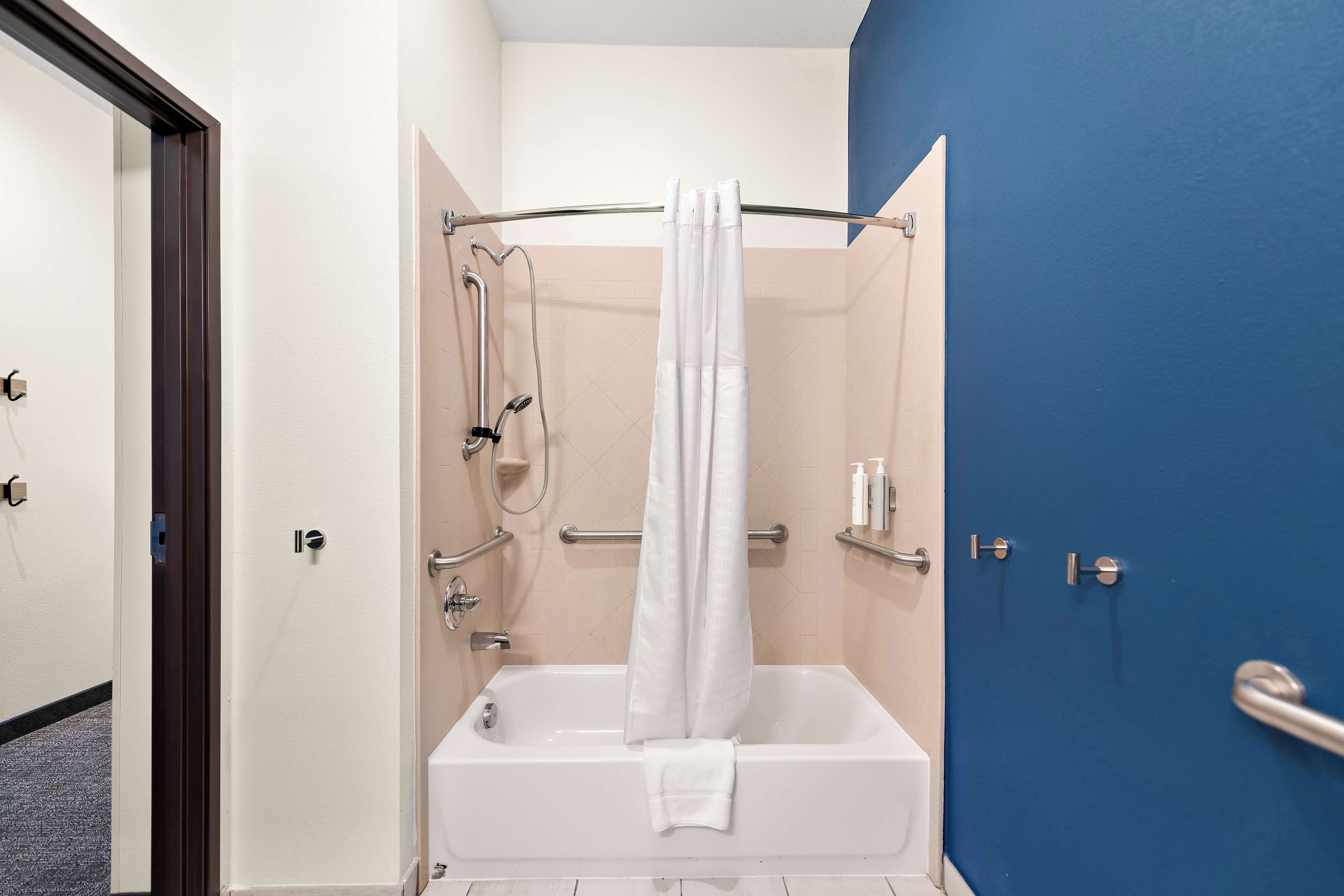 A bathroom with a bathtub, a shower, and a blue wall.